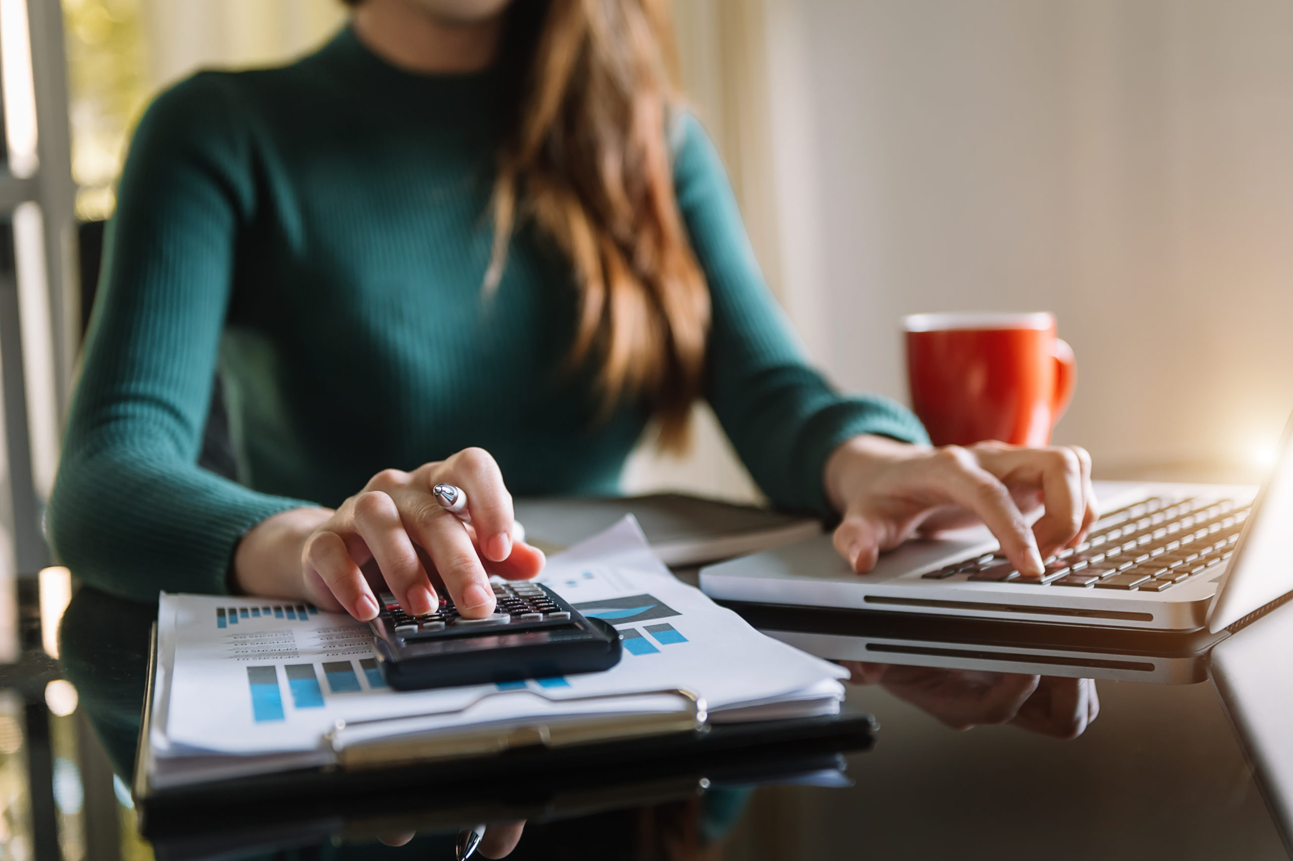 Businesswoman working on office desk using a calculator